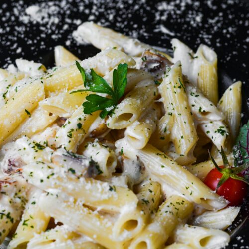 a plate of pasta with parmesan cheese and a cherry