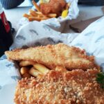 A fish and chips meal with a soda