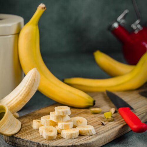 yellow banana fruit on brown wooden chopping board